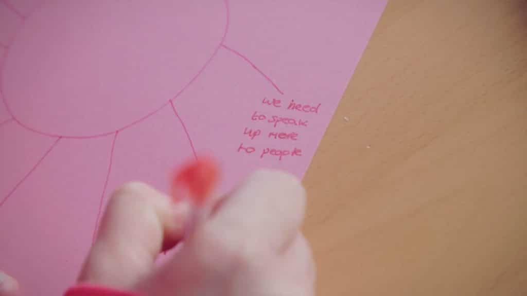 pink paper with hand written text saying 'we need to speak up more to people'