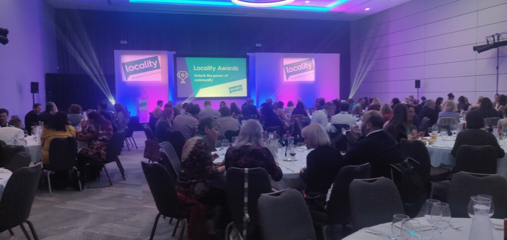 Photograph taken at the previous year's awards dinner showing crowd and stage with Locality branding