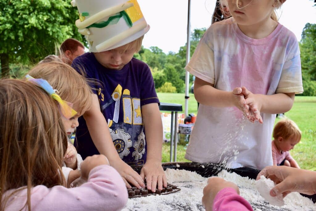 Photo of children playing around a raised sandpit fill with flour